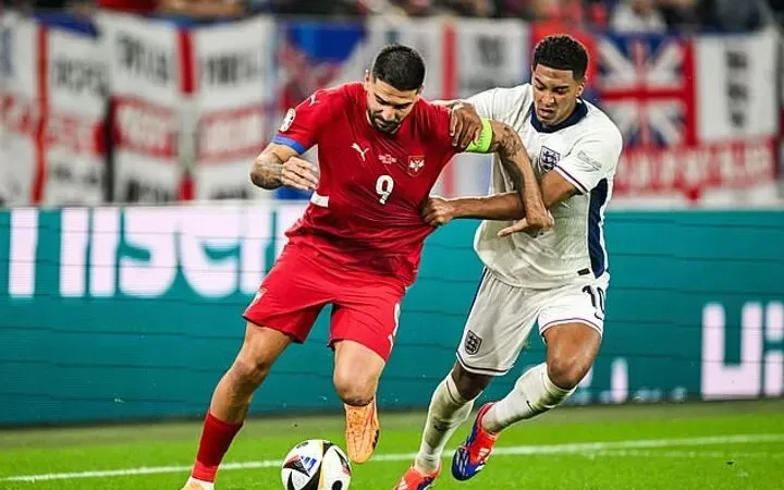 Jude Bellingham (phải) co về phòng thủ trước Aleksandar Mitrovic