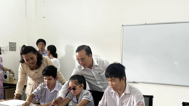 Ông Nguyễn Ngọc Thắng, Phó tổng giám đốc Saigon Co.op đang hướng dẫn các em học sinh học tiếng Anh với bộ sách chữ nổi