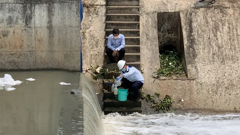 Lực lượng chức năng lấy mẫu nước xét nghiệm