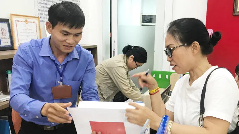 Công chức phường Bến Thành, quận 1, TPHCM đang tiếp nhận, chứng thực hồ sơ sao y của người dân ngoài giờ hành chính. Ảnh: KIỀU PHONG