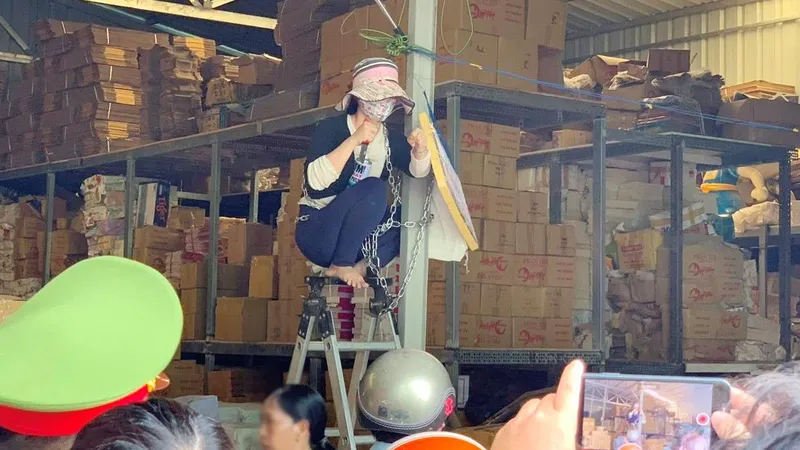 Người dân ngồi trên ghế, xích mình vào cột và lăm lăm dao trên tay để tạo áp lực với đoàn cưỡng chế