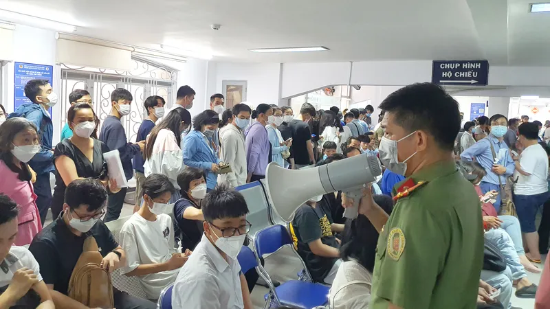 Cán bộ Phòng PA08 thông báo về việc tạm ngưng cấp số thứ tự và hướng dẫn người dân đăng ký cấp hộ chiếu online. Ảnh: NGÔ BÌNH