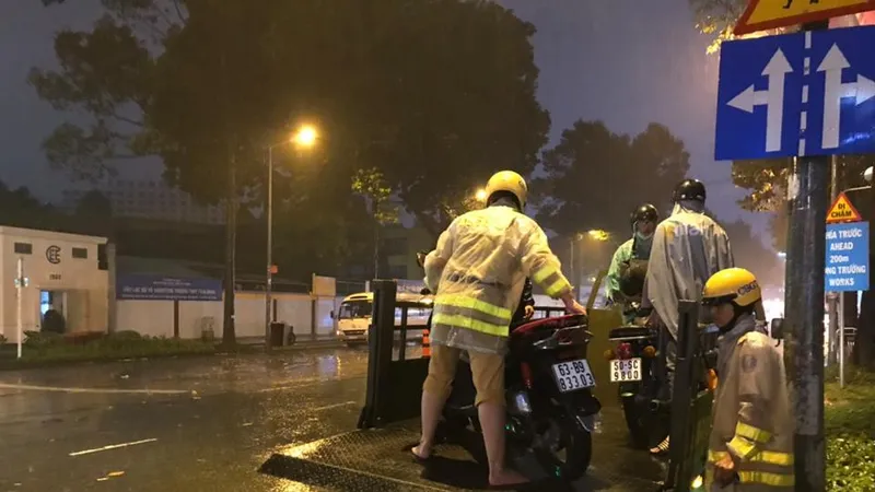 Hình ảnh CSGT giúp dân đưa xe vượt điểm ngập trong cơn bão số 9 ở trung tâm TPHCM. Ảnh: ĐAN NGUYÊN