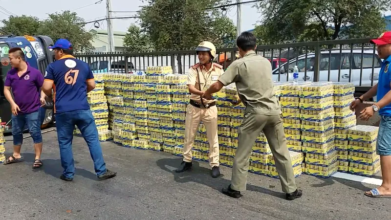 Người dân cùng CSGT dọn hàng trăm thùng nước ngọt giúp tài xế. Ảnh: CHÍ THẠCH 
