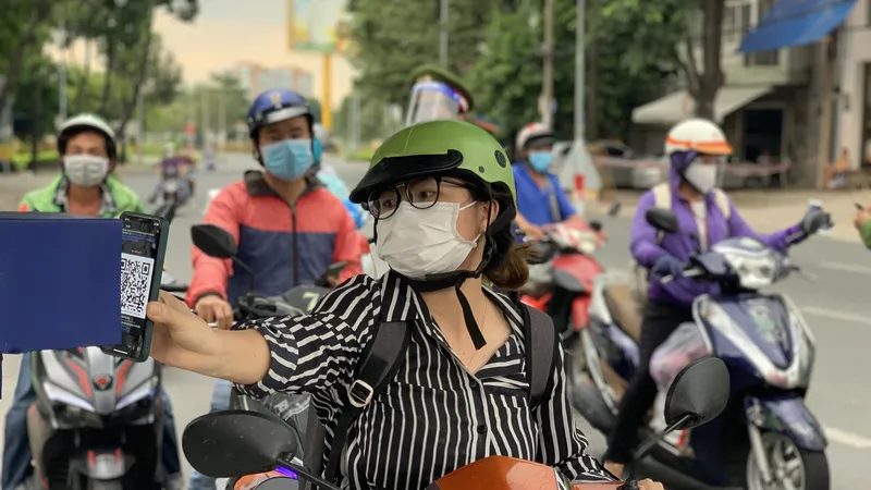Người dân đi đường đưa mã QR vào camera được gắn tại đây để quét mã tại chốt đường Đinh Bộ Lĩnh, quận Bình Thạnh chiều 7-9. Ảnh: CHÍ THẠCH 
