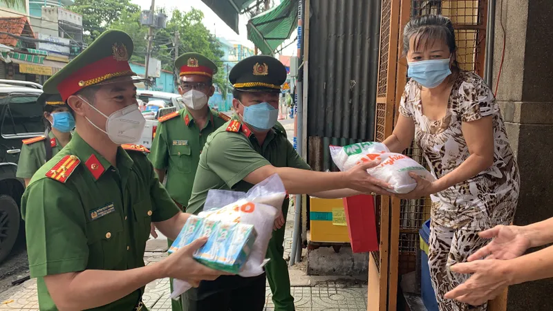 Thượng Tá Trần Anh Thanh, Phó Trưởng Phòng PX03, Công an TPHCM cùng Thượng tá Huỳnh Trung Phong, Trưởng Công an quận 6 gõ cửa nhà dân trao các phần quà hỗ trợ. Ảnh: CHÍ THẠCH 