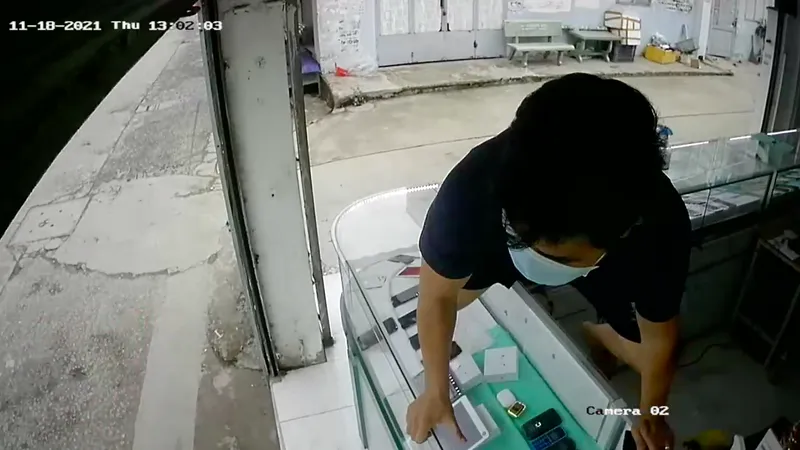Chủ tiệm leo qua tủ kính truy đuổi thanh niên vờ mua rồi cướp điện thoại