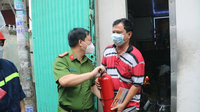 Đại tá Huỳnh Quang Tâm, Trưởng phòng PC07 trao bình chữa cháy cho người dân. Ảnh: C.T