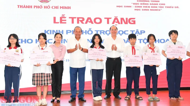 Phó Bí thư Thành ủy TPHCM Nguyễn Hồ Hải cùng nguyên Phó Thủ tướng Thường trực Trương Hòa Bình trao kinh phí hỗ trợ cho các em học sinh. Ảnh: VIỆT DŨNG 