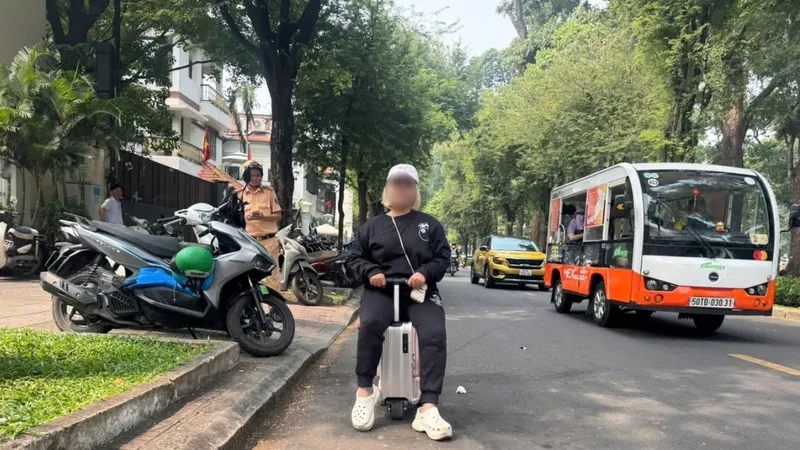 Người phụ nữ cưỡi vali chạy trên đường ở trung tâm TPHCM