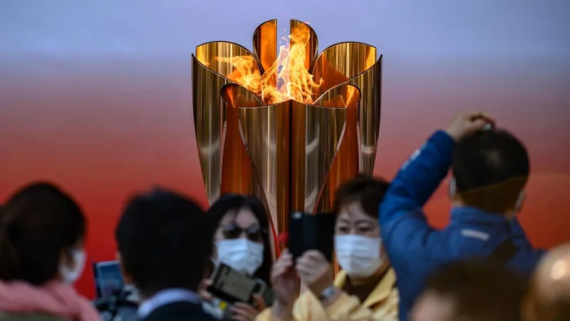 Nhiều du khách đeo khẩu trang vẫn đến thăm đài lửa Olympic Tokyo 