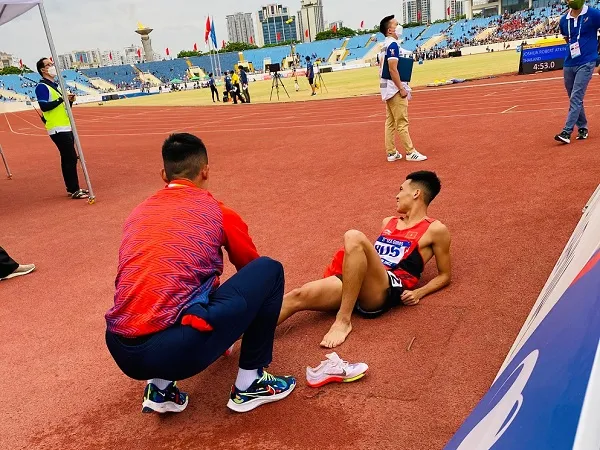 Nguyễn Tiến Trọng nhanh chóng giúp người đồng đội Trần Văn Đảng cởi giầy, sơ cứu ngay khi bị đau sau khi kết thúc thi đấu 800m. Ảnh: MINH CHIẾN