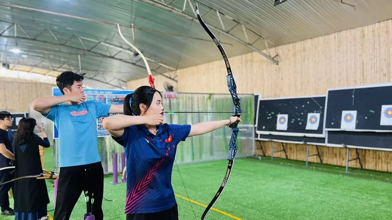 Ánh Nguyệt hướng dẫn Đức Phát làm quen với bắn cung để thêm hiểu hơn môn thể thao của mình. Ảnh: Đ.A.NGUYỆT