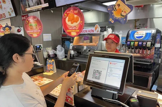 Customers are making electronic payments when purchasing goods at a fast-food store in Xom Chieu Ward of HCMC (Photo: SGGP)