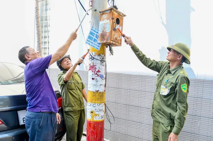Grassroots security forces and residents of Tam Thang Ward are eradicating illegal advertisements (Photo: SGGP)