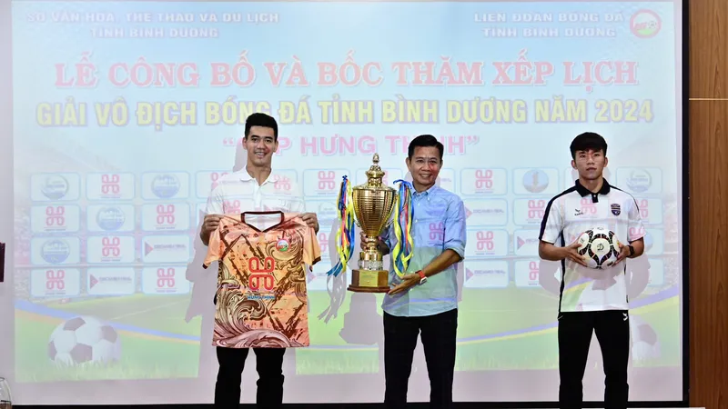 HLV Hoàng Anh Tuấn cùng cầu thủ Tiến Linh giới thiệu Cúp vô địch và áo thi đấu tại giải.