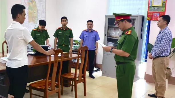Công an đọc quyết định khởi tố đối với ông Hưng (áo trắng). Ảnh: Công an Gia Lai