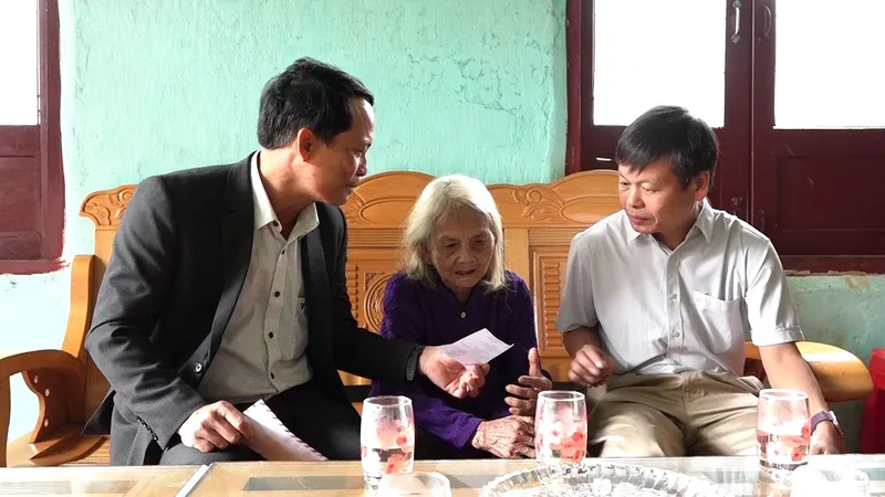 Ông Võ Trung Mạnh (bên trái), Bí thư Đảng ủy, Chủ tịch Ủy ban bầu cử xã Tu Mơ Rông, và ông Trần Quốc Huy (bên phải), Chủ tịch UBND xã, thăm, phát thẻ cử tri cho Mẹ Việt Nam anh hùng Y Tría, đồng thời động viên mẹ yên tâm chăm sóc sức khỏe
