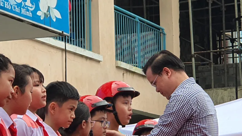 Thầy Trần Nguyễn Minh Thành trao tặng mũ bảo hiểm cho các em học sinh lớp 5 có hoàn cảnh gia đình khó khăn