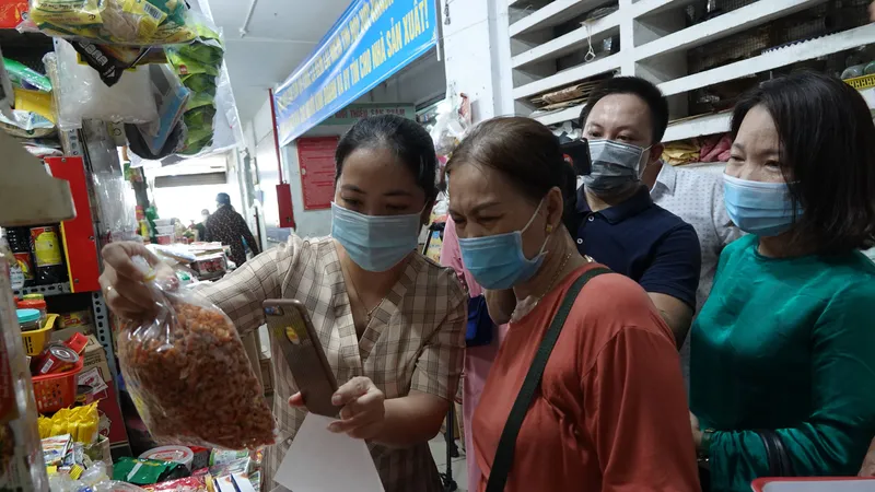 Thành viên Ban quản lý các chợ quận Hải Châu hướng dẫn người dân quét mã QR Code trên điện thoại thông minh