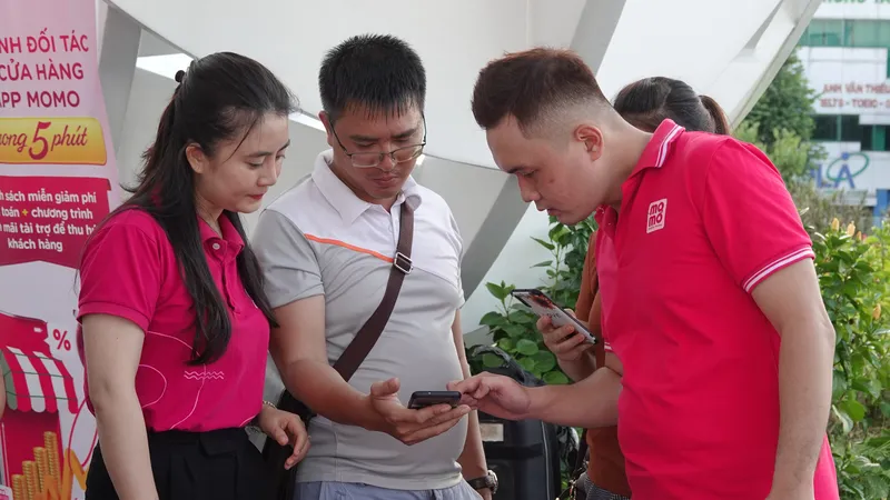 Các nhân viên đang hướng dẫn người dân thực hiện thanh toán không tiền mặt