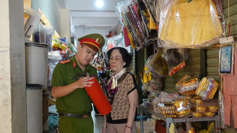 Công an hướng dẫn, kiểm tra cách sử dụng bình chữa cháy của tiểu thương các chợ. Ảnh: XUÂN QUỲNH