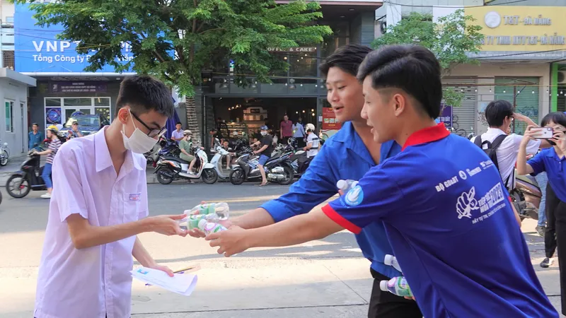 Các tình nguyện viên hỗ trợ tiếp nước cho thí sinh trước điểm trường. Ảnh: XUÂN QUỲNH