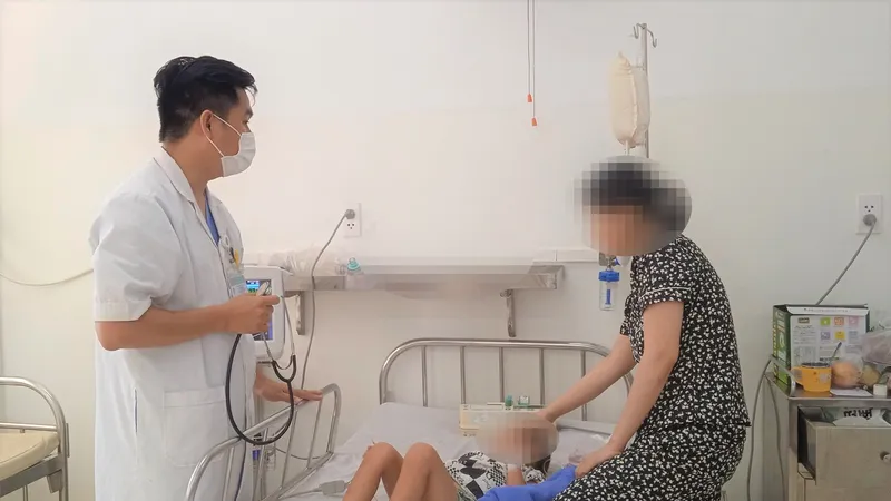 Bác sỹ Nguyễn Hải Thịnh đang khám bệnh cho con của chị Lê Thị Ngọc Châu. Ảnh: XUÂN QUỲNH