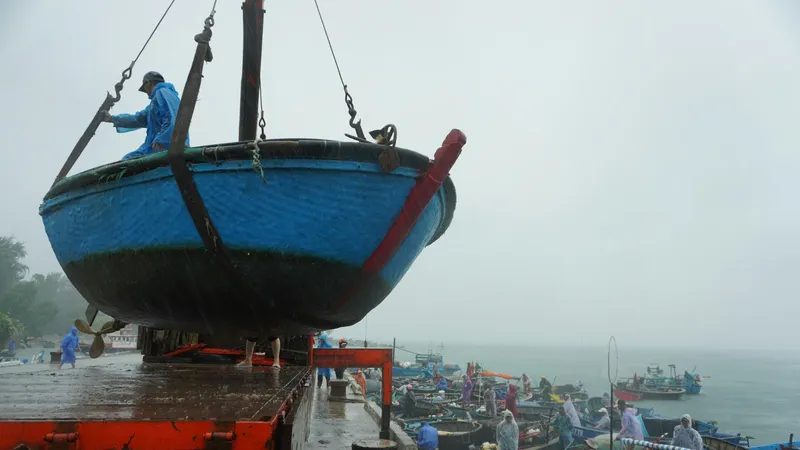 Dưới cơn mưa lớn, ngư dân Đà Nẵng hối hả kéo, cẩu ghe, thuyền, thúng lên bờ. Ảnh: XUÂN QUỲNH