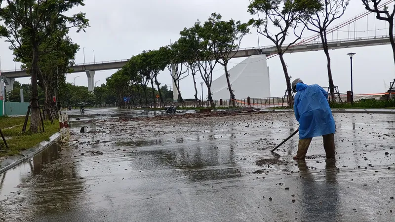 Lực lượng chức năng cào dọn lớp đất, cát bị sóng đánh tràn vào. Ảnh: XUÂN QUỲNH