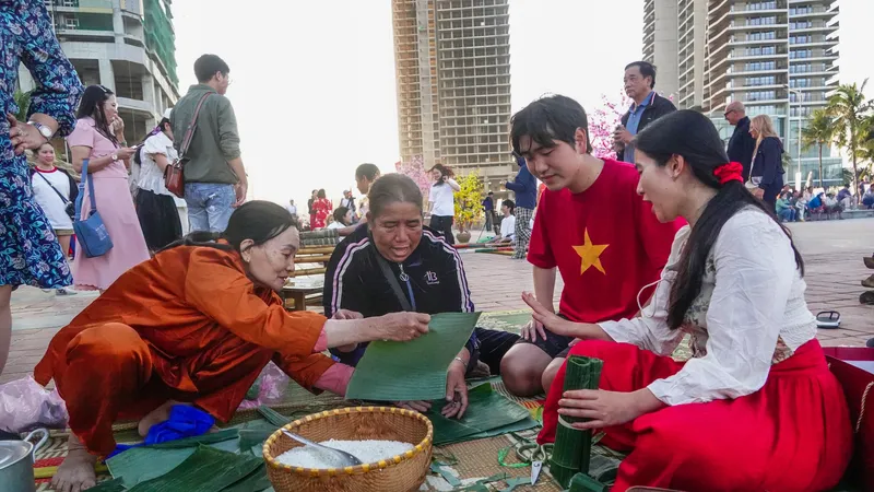 Du khách tập gói bánh tét. Ảnh: XUÂN QUỲNH