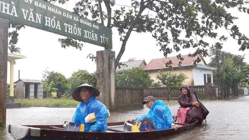 Người dân huyện Quảng Điền, tỉnh Thừa Thiên - Huế di chuyển trên đường ngập lụt, chiều 17-10. Ảnh: VĂN THẮNG