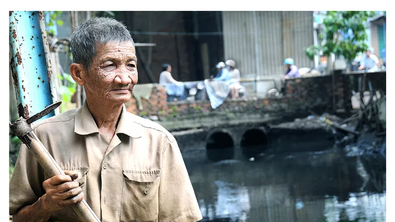 Bác Bảy Tân - nhân vật trong bộ ảnh “Người thầm lặng 30 năm vớt rác trên dòng kênh đen”. Ảnh: NSNA AN DUNG