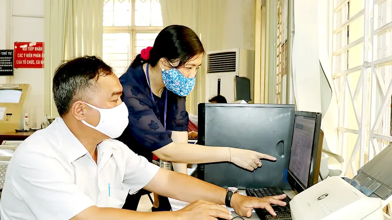 Công chức quận Bình Thạnh hướng dẫn người dân nộp hồ sơ trực tuyến. Ảnh: HỒNG HẢI