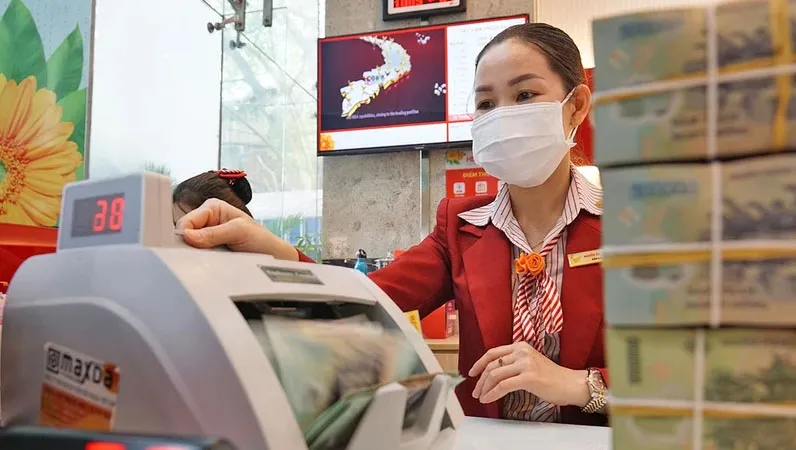 Nhân viên một ngân hàng đang kiểm tra tiền gửi tiết kiệm của khách hàng. Ảnh: HOÀNG HÙNG