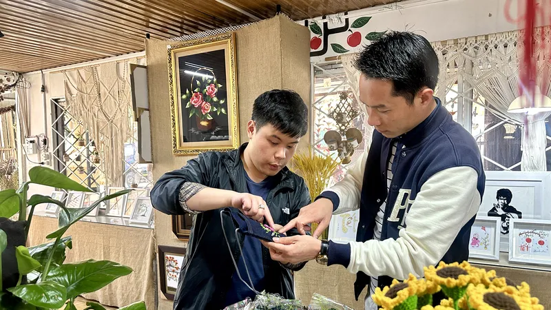 Nguyễn Lưu Quang, học sinh Trường Khiếm thính Lâm Đồng (bên trái), giới thiệu cho khách những sản phẩm do chính các bạn khiếm thính làm ra