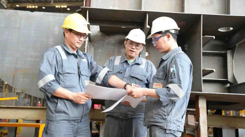 Kỹ sư Nguyễn Văn Lộc (bên trái) trao đổi kỹ thuật với đồng nghiệp trong giờ làm việc (ẢNH: TRÚC GIANG)