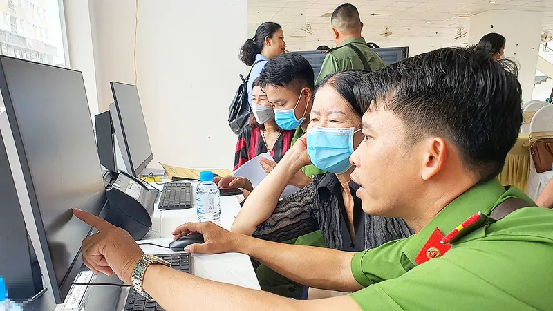 Cán bộ Công an quận 12 (TPHCM) hướng dẫn người dân đăng ký tài khoản Dịch vụ công trực tuyến. Ảnh: NGÔ BÌNH