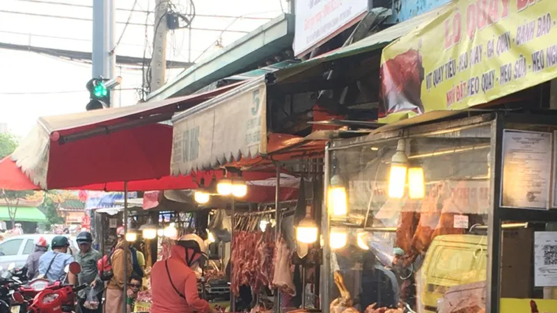 Người đi đường dựng xe trên đường đứng mua thịt heo tại chợ tự phát Hiệp Bình, TP Thủ Đức, TPHCM