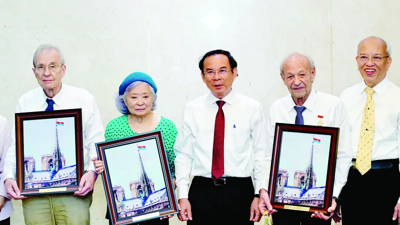 Bí thư Thành ủy TPHCM Nguyễn Văn Nên tặng ông Olivier Parriaux (bìa trái), ông Bernard Bachelard và bà Trần Tố Nga tranh gạo. Ảnh: HOÀNG HÙNG