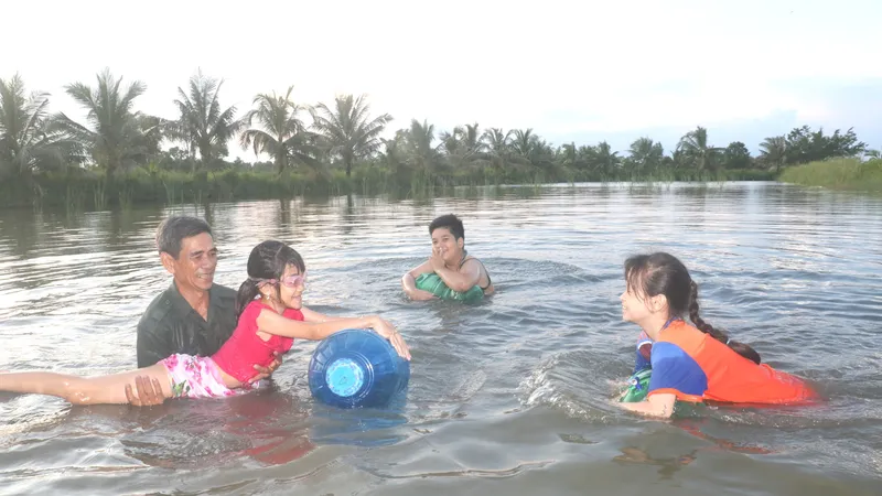 Các em học sinh tập bơi trong vuông tôm, để trang bị kỹ năng phòng chống đuối nước tại phường 9, TP Cà Mau, tỉnh Cà Mau. Ảnh: TẤN THÁI