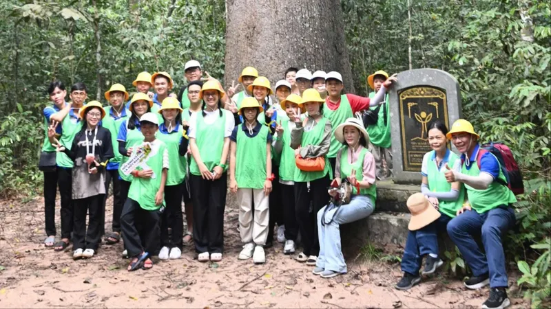 Các em học sinh chụp ảnh trước cây Vên Vên - một trong hai cây Di sản Việt Nam ở Vườn quốc gia Lò Gò - Xa Mát