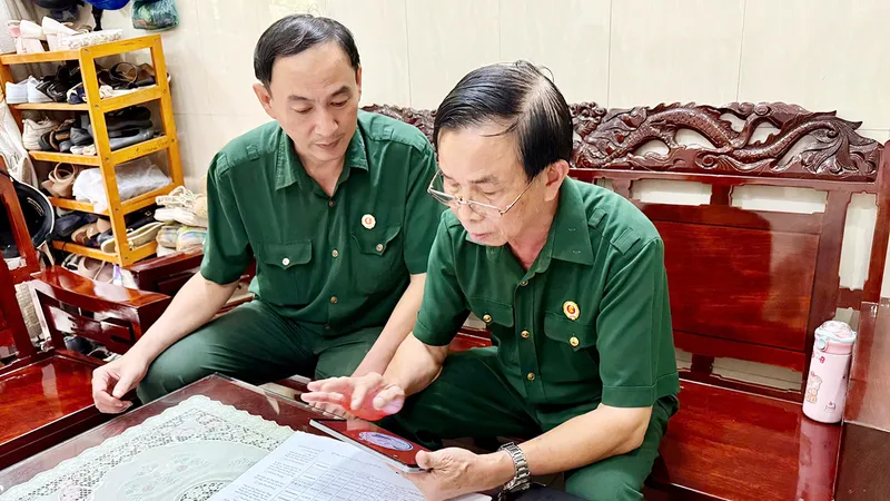 Ông Nguyễn Ngọc Thám, người cựu chiến binh với vai trò Bí thư Chi bộ khu phố 20 phường Minh Phụng (bên phải), thuần thục với các thao tác trên phần mềm điện tử. Ảnh: CẨM NƯƠNG