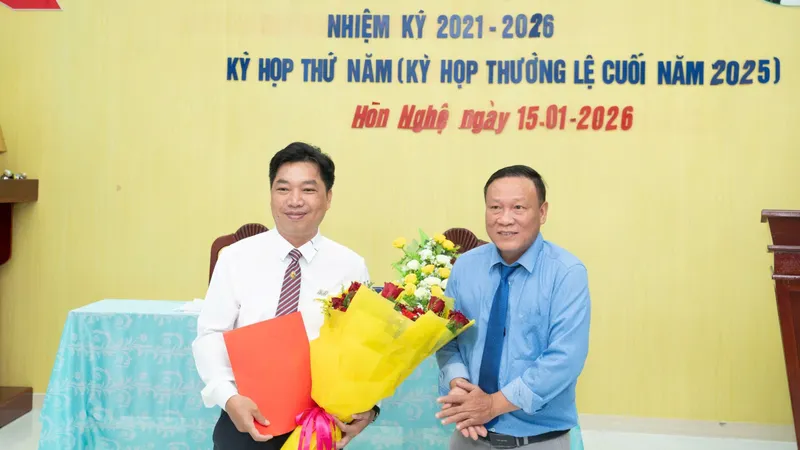 Nhà báo Ngô Ngọc Chuẩn (trái) nhận hoa chúc mừng của Bí thư Đảng ủy xã Hòn Nghệ