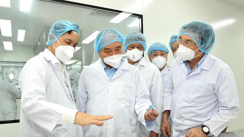 Chủ tịch nước Nguyễn Xuân Phúc và Bí thư Thành ủy TPHCM Nguyễn Văn Nên nghe giới thiệu về vaccine Nano Covax. Ảnh: VIỆT DŨNG