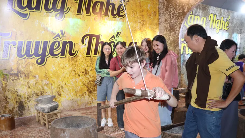 Du khách nước ngoài thích thú trải nghiệm các mô hình làng nghề truyền thống tại lễ hội. Ảnh: QUANG VŨ