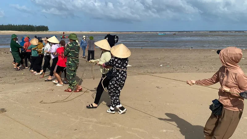 Người dân cùng bộ đội biên phòng kéo tào bị chìm vào bờ