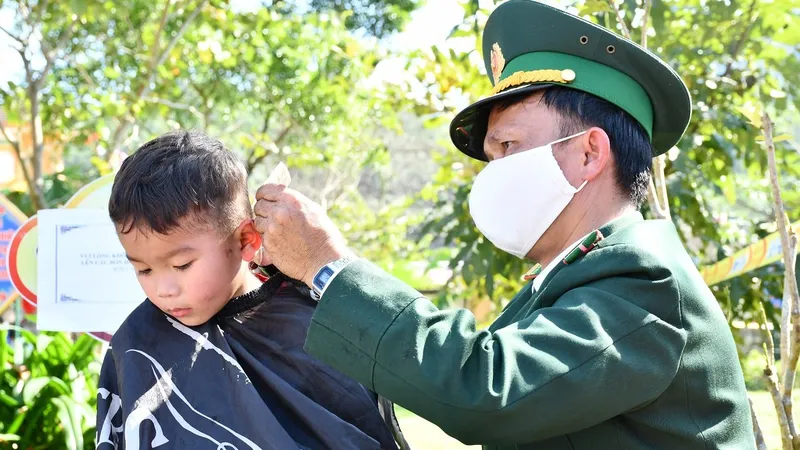 Người lính quân hàm xanh cắt tóc cho trẻ em Vân Kiều, bản Rum Ho, xã Kim Thủy, huyện Lệ Thủy để đón tết