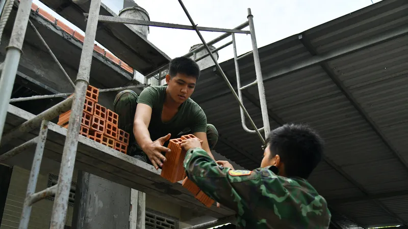 Chiến sĩ lực lượng vũ trang tỉnh Kiên Giang hỗ trợ cất nhà cho hộ nghèo. Ảnh: QUỐC BÌNH