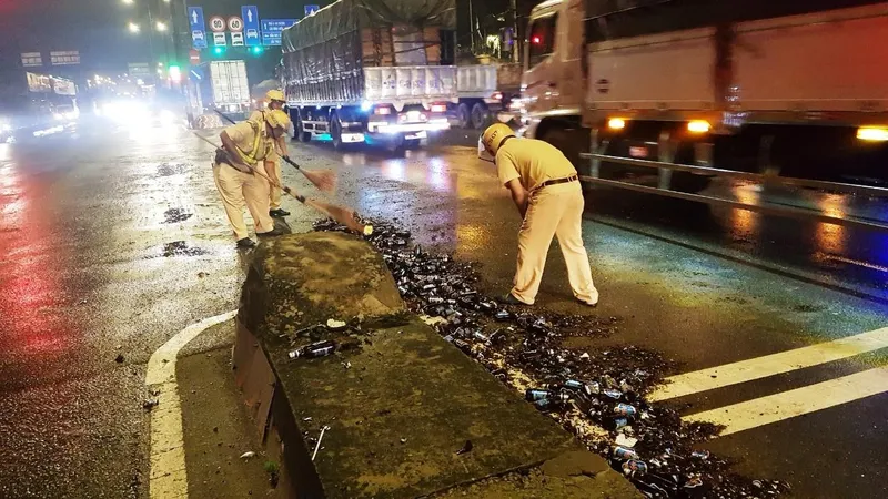 Cảnh sát giao thông hỗ trợ công nhân vệ sinh thu dọn vỏ chai đổ trên đường